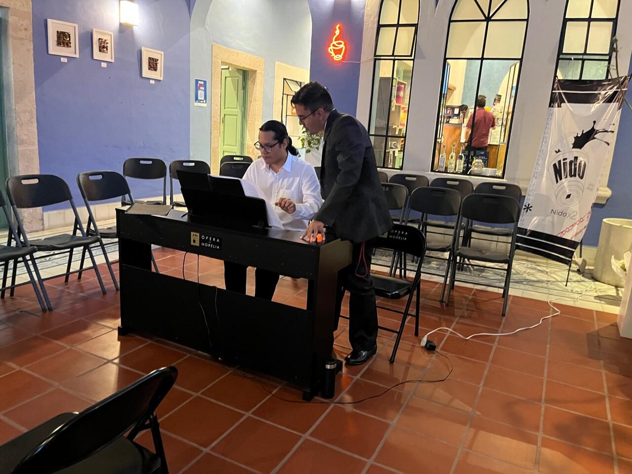 Pianista en azul de espalda con banner de Cultural Nido detrás