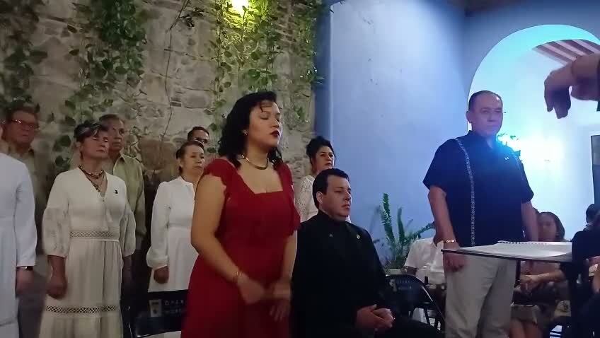 Natali Juárez canta una aria con los ojos cerrados, Omar Nieto dirige a la derecha